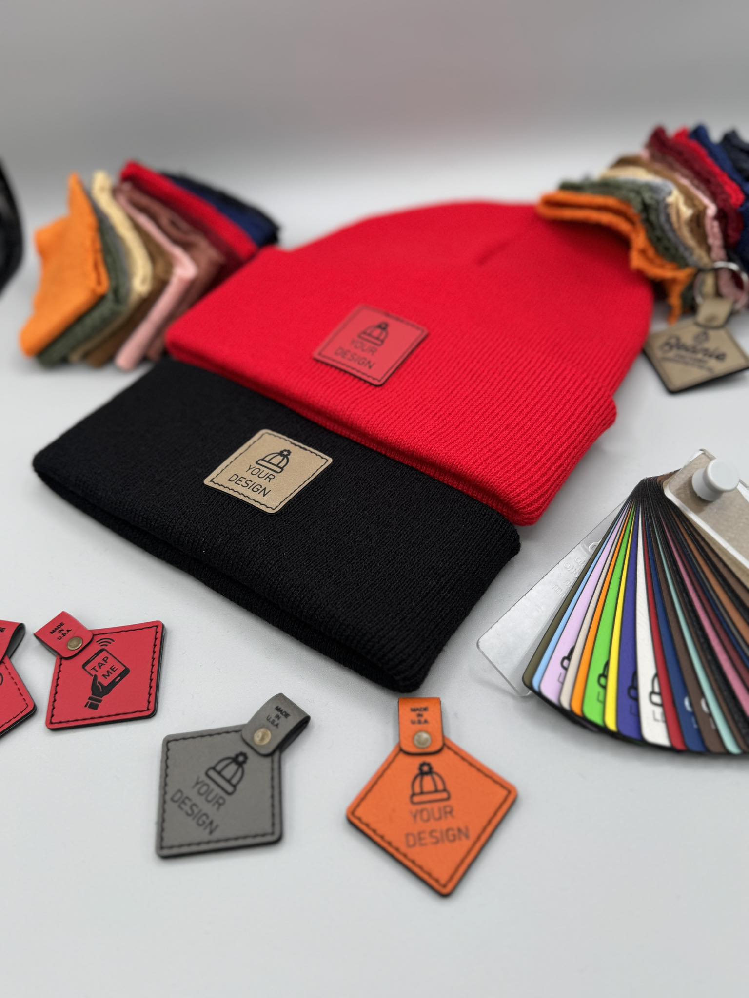 Collection of colorful leather tags and a red beanie on a gray background