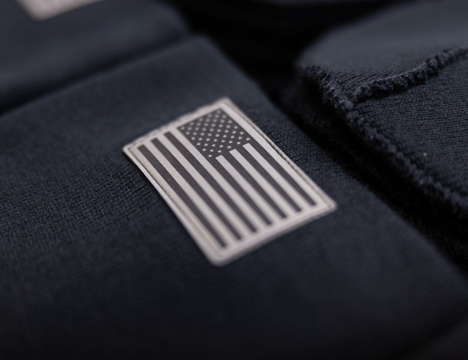 A close-up of an American flag on fabric. The Beanie Factory products are customizable with elements like woven patches, embroidery, and laser-engraved leatherette patches.