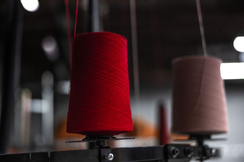 Two spools of thread are in use on a piece of machinery in The Beanie Factory's manufacturing facility in Parma, Ohio.
